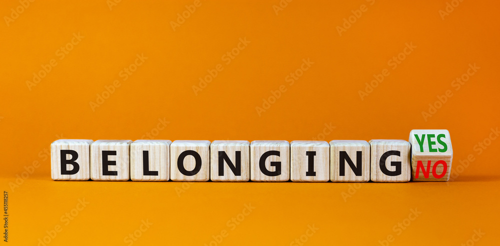 Belonging yes or no symbol. Turned a wooden cube and changed words 'belonging no' to 'belonging yes'. Beautiful orange background. Business and belonging yes or no concept, copy space.