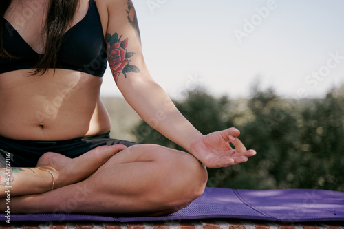 Unrecognisable young yogi woman practising yoga meditation, sitting in siddhasana, meditation session in nature. photo