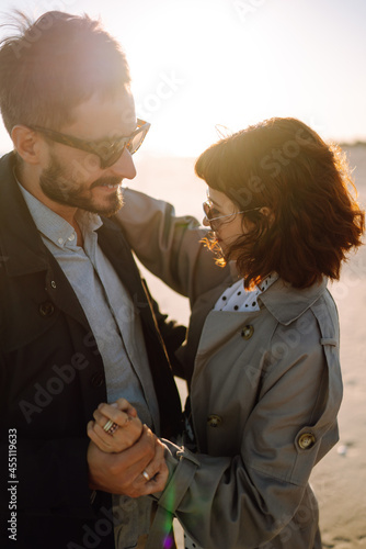 Young couple having fun walking and hugging on beach during autumn sunny day. Relaxation, youth, love, lifestyle solitude with nature.