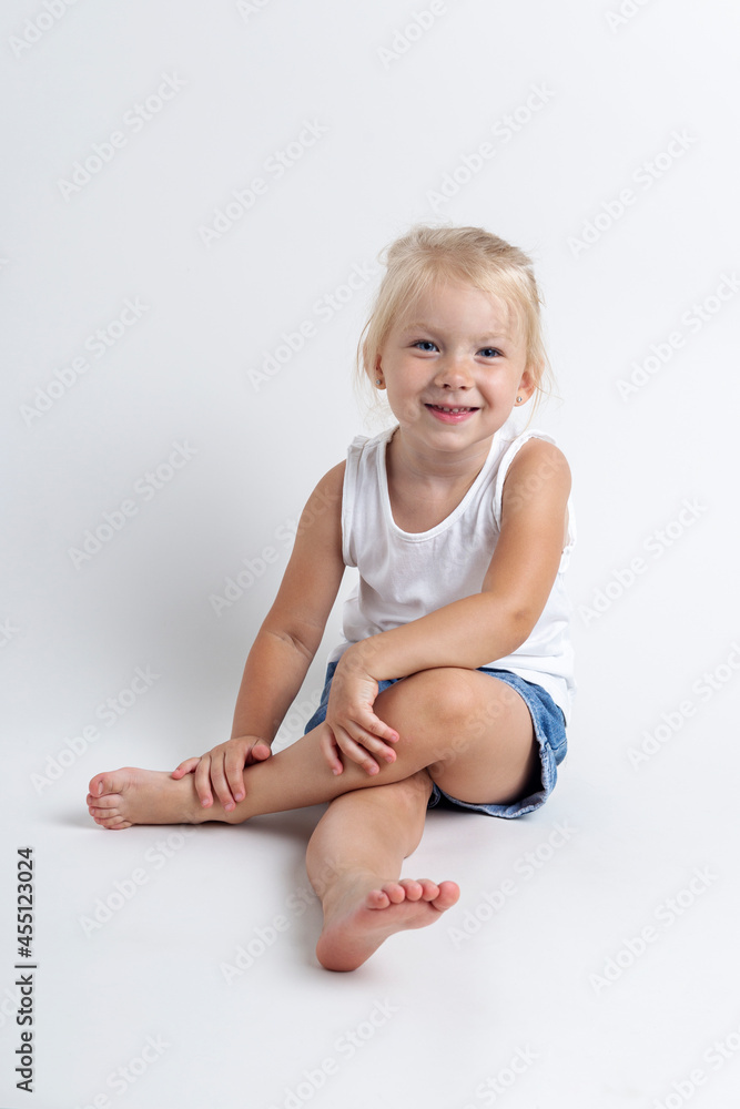 Child in a T-shirt, shorts sitting in the studio on a light background Child in a T-shirt, shorts sitting in the studio on a light background