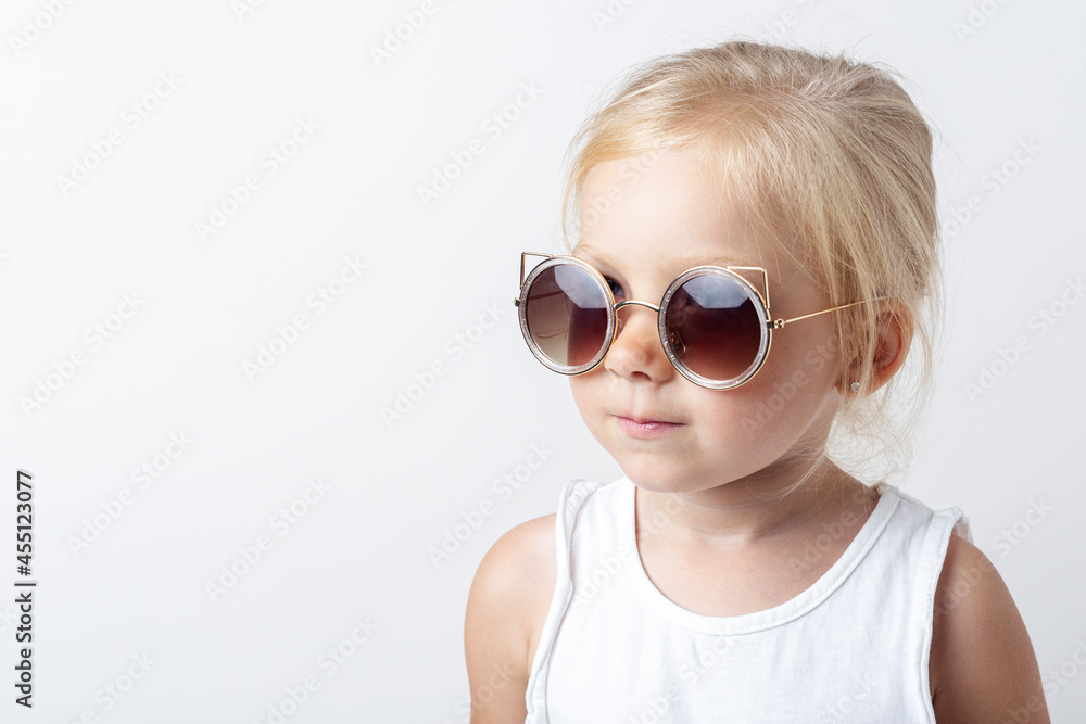 Beautiful blonde child in sunglasses on a light studio background Beautiful blonde child in sunglasses on a light studio background