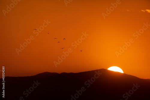 The silhouette of the mountains against the background of the sun. Sunrise or sunset with the silhouette of birds.