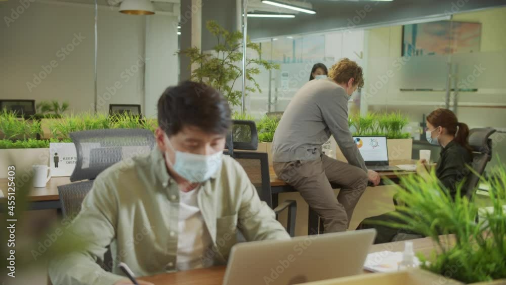 A young man is working and his colleagues are discussing on a project A young man is working and his colleagues are discussing on a project