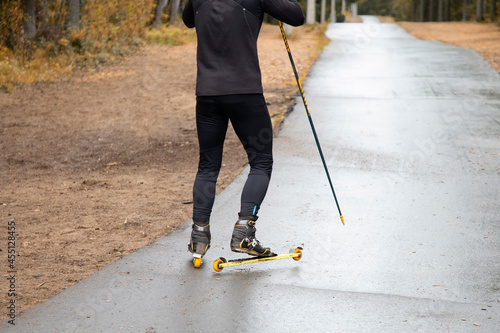 A man on a roller ski rides in the park.Cross country skilling. photo