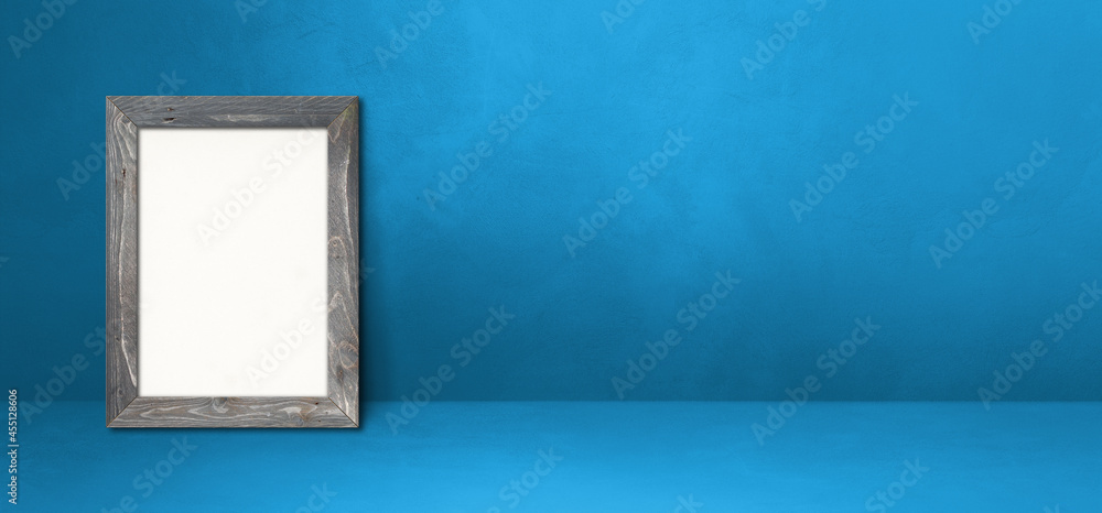 Wooden picture frame leaning on a blue wall. Horizontal banner Wooden picture frame leaning on a blue wall. Horizontal banner