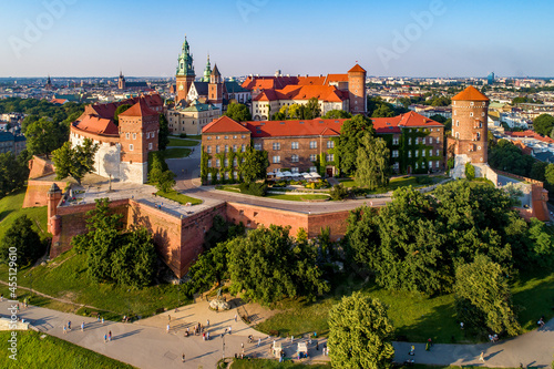 Krakow, Poland. Historic royal Wawel castle and cathedral. Aerial view at sunset in summer. Old town with St. Mary church in the background. Park, promenades and walking people