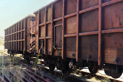 vintage abandoned train carriages on the tracks with rusty red surface in the summer