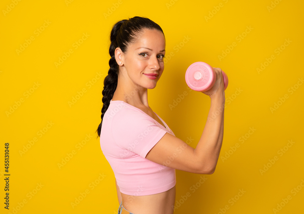 Young woman with a dumbbell isolated on yellow background doing strong gesture Young woman with a dumbbell isolated on yellow background doing strong gesture