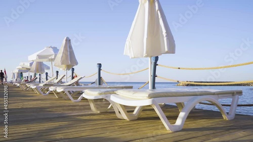 Isolated white deck chairs on a wooden pier. A resort holiday by the sea. The concept of rest and vacation.