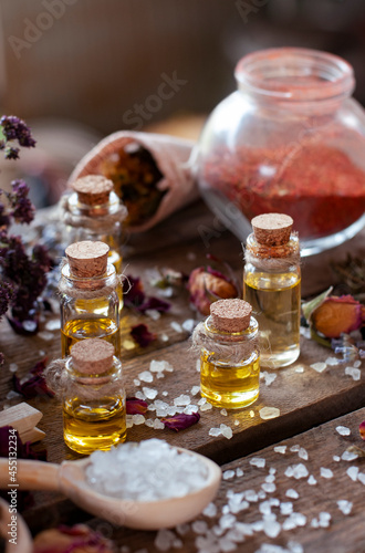 Fototapeta Naklejka Na Ścianę i Meble -  essential oil bottles with dry ingredients of lavender, oregano and rose on the wood table	