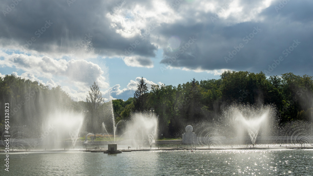 Water from the fountain. Top of high water stream of fountain behind cloudy sky. Fountain in river against dramatic sky. Cityscape view. Water from the fountain. Top of high water stream of fountain behind cloudy sky. Fountain in river against dramatic sky. Cityscape view.