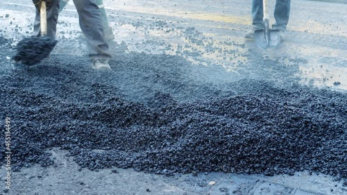 workers throw hot asphalt on the road compaction of pavement in road