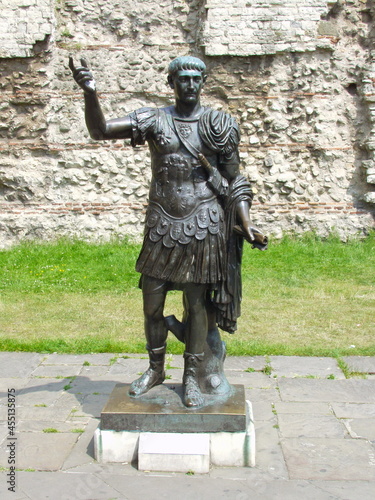 Statue of Roman Emperor Trajan in front of Roman walls in London, Uk. photo