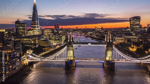 Forwards reveal of city lights of large town at dawn. Amazing hyperlapse of fly over Tower Bridge. Modern skyscrapers on both Thames river banks. London, UK photo