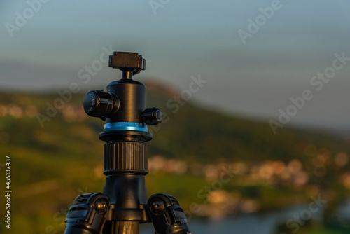 Tripod with ball head in green mountains with sunset orange light