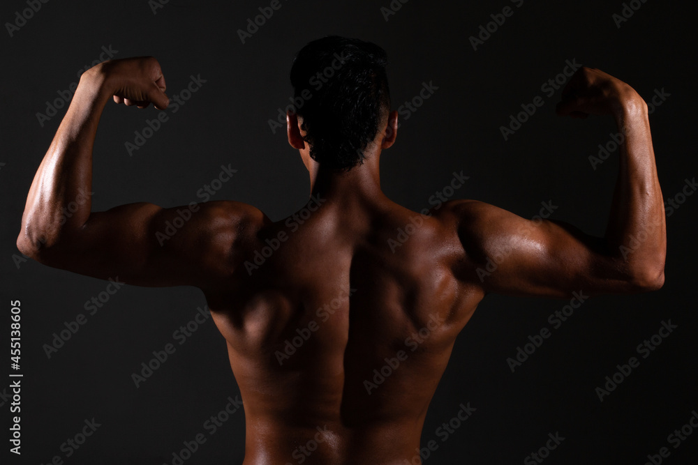 Bodybuilder showing his back and biceps muscles, personal fitnes.Brown-skinned man
