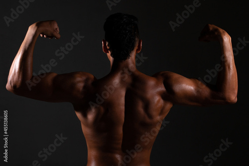 Bodybuilder showing his back and biceps muscles, personal fitnes.Brown-skinned man
