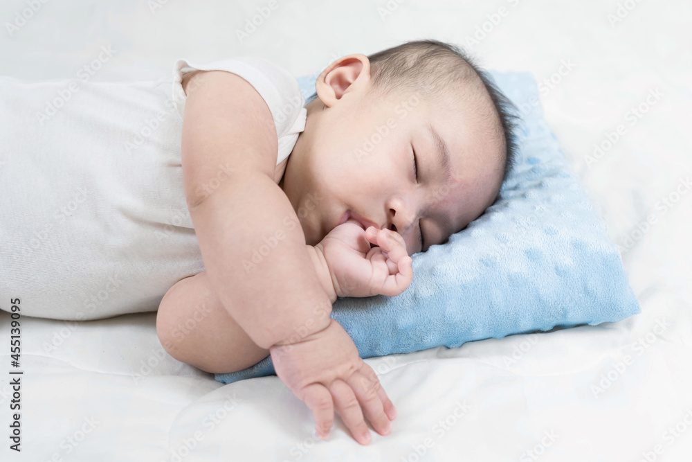Charming baby boy sleeping on comfortable bed.Adorable asian newborn sucking thump.This is growth development behavior. Charming baby boy sleeping on comfortable bed.Adorable asian newborn sucking thump.This is growth development behavior.