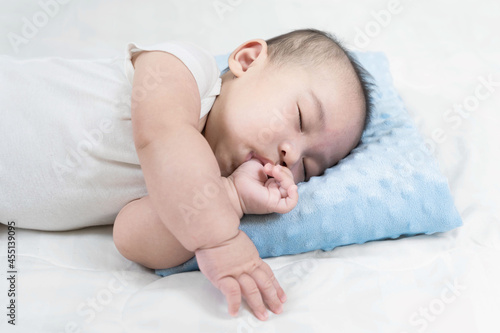 Charming baby boy sleeping on comfortable bed.Adorable asian newborn sucking thump.This is growth development behavior.