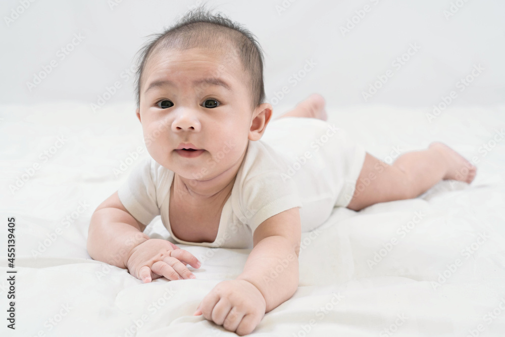 Training tummy time.Portrait of adorable young Asian newborn little baby boy prone on the bed, the child's brain will work.