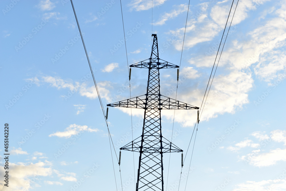 High-voltage power lines are very high in the forest against the sky