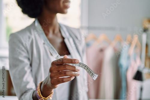 Close-up of young African woman using tape measure while working in design studio