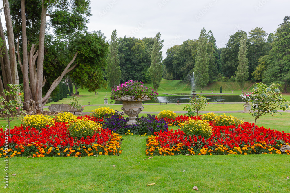 View through the colourful flower beds down to the lake  with the fountain and woodland background