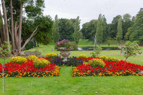 View through the colourful flower beds down to the lake with the fountain and woodland background