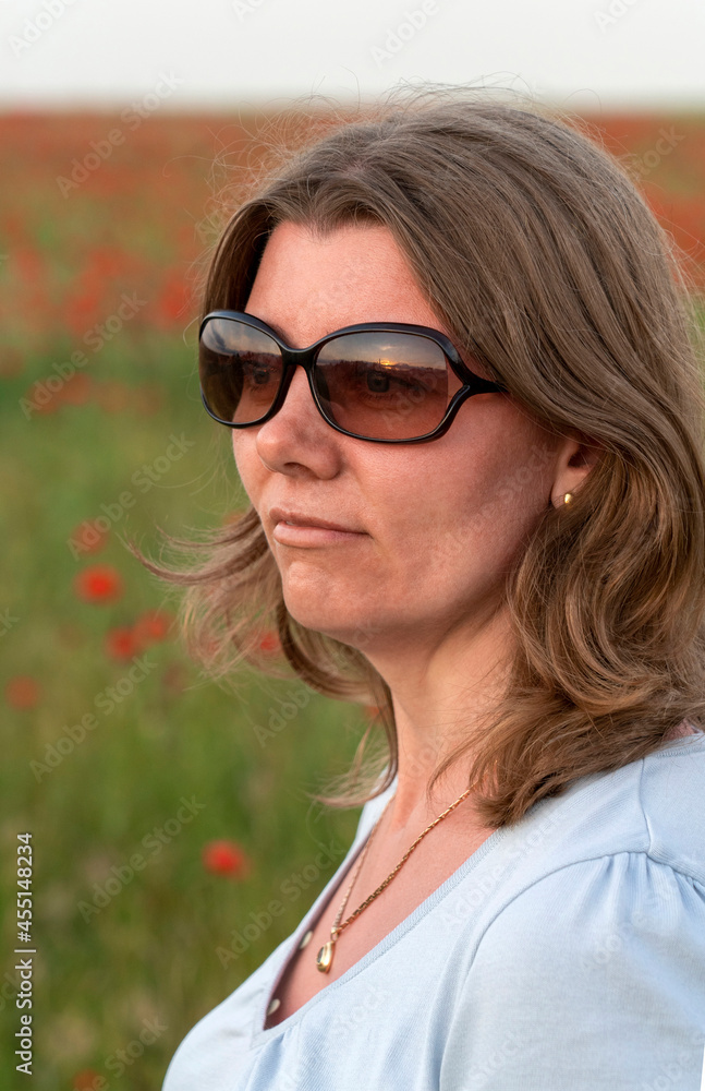 Portrait of happy woman in field of poppies at sunset. Concept freedom, happiness, calm and summer vacation Portrait of happy woman in field of poppies at sunset. Concept freedom, happiness, calm and summer vacation