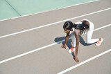 Top view of beautiful young African woman standing at starting position on running track outdoors