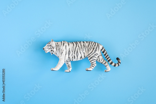 the tiger  symbol of 2022 year. plastic white toy figure tiger on a blue background. top view