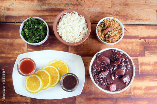 typical Brazilian food feijoada made with beans, pork, bacon, sausage with cabbage, rice, salad, spices and pepper.