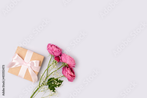 Present with a tied ribbon and bouquet of flowers on a blue background. Gift for Mothers Day with copyspace.