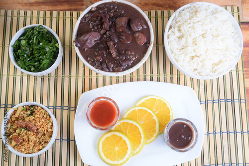 typical Brazilian food feijoada made with beans, pork, bacon, sausage with cabbage, rice, salad, spices and pepper.