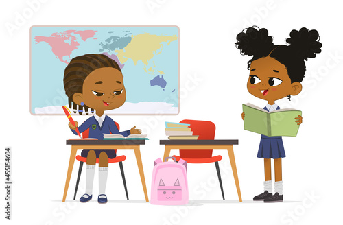 Cheerful schoolgirl classmates talking at geography class with map wearing school uniform vector flat illustration. Cute little primary pupils studying at multiracial class sitting at table with books