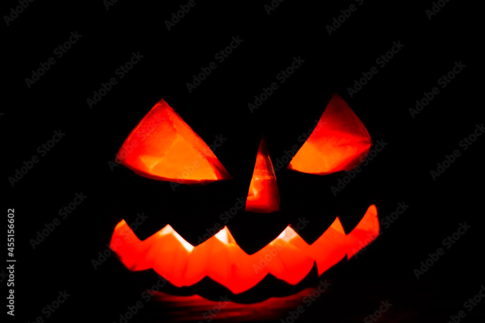 Carved halloween pumpkin jack-o-lantern glows in a darkness Carved halloween pumpkin jack-o-lantern glows in a darkness
