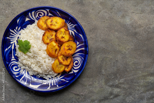 Canvas Print Rice and fried banana also called cuban style on dark background