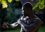 Attractive young athlte exercising shirtless in yard.