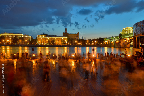 blurred people on night embankment of Moscow