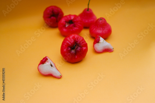 Freshly rose apple fruit isolated on orange background. Also known as jambu air Merah (Syzygium aqueum), jambu Semarang (Syzygium samarangense), Jambu Bol, or Malay Apple (Syzygium malaccense) photo