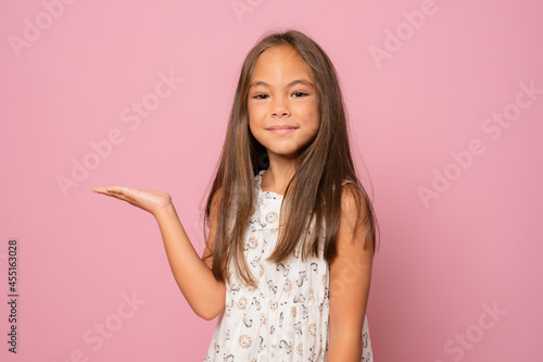 Kid happy smiling face show something on open palm copy space. Girl demonstrate product. Advertisement and commercial concept.