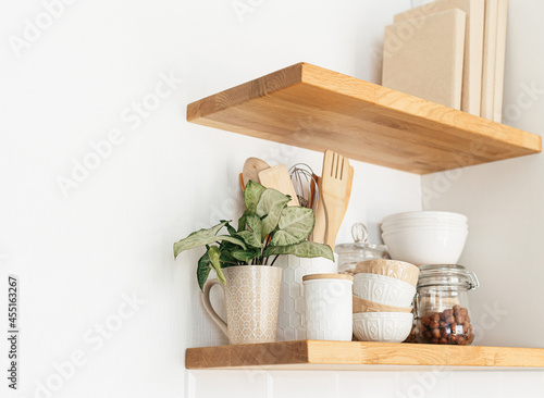 Kitchen shelves with various white ceramic, glass jars, cooking book. Open shelves in the kitchen. Kitchen interior open shelving ideas. Eco friendly kitchen, zero waste home concept photo