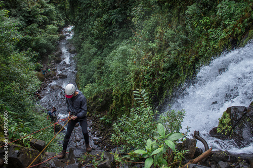 horizontal shot of man rappelling down a large waterfall in the middle of the tropical forest in Costa Rica