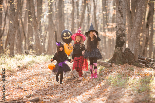 three little girls in witch costumes laugh, conjure, walk through the autumn forest with baskets for sweets in the shape of pumpkins. halloween concept, lifestyle . High quality photo © КРИСТИНА Игумнова