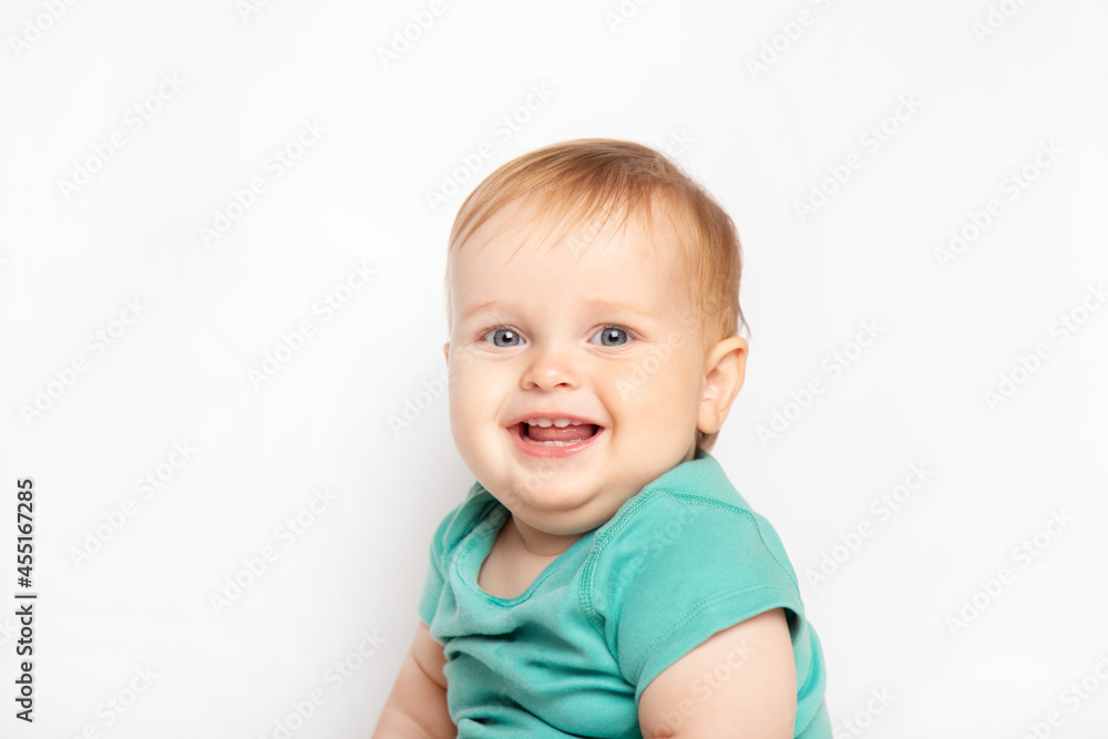 Infant child baby boy in green t-shirt laughs happy looking at the camera isolated on a white background. Childcare and upbringing concept.
