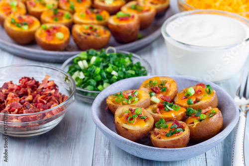 Baked mini red skinned loaded potatoes with crispy bacon, scallions and sharp cheddar cheese, horizontal