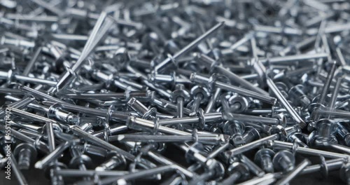 Aluminum rivets fall onto a rotating pile of metal rivets. Close-up. photo