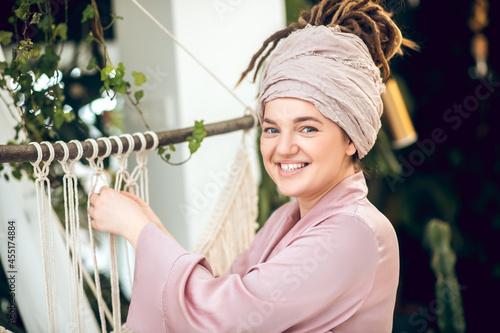 Smiling pretty woman doing macrame weaving photo