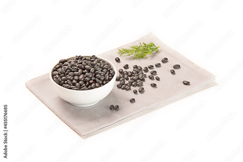 frijol negro seco en un bol blanco sobre una servilleta de tela gris con una ramita de eneldo, aislada recortada en fondo blanco frijol negro seco en un bol blanco sobre una servilleta de tela gris con una ramita de eneldo, aislada recortada en fondo blanco