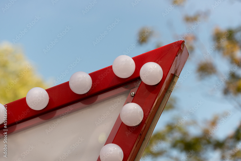 detail close up of a red sign with globe light bulbs on a blue sky